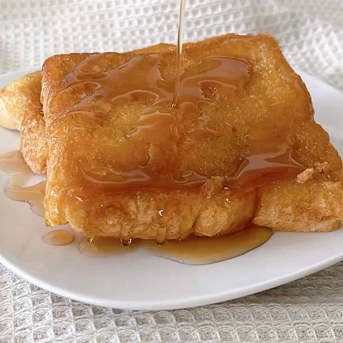 A slice of Crème Brûlée French Toast with maple syrup.