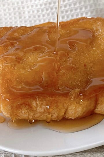A slice of Crème Brûlée French Toast with maple syrup.