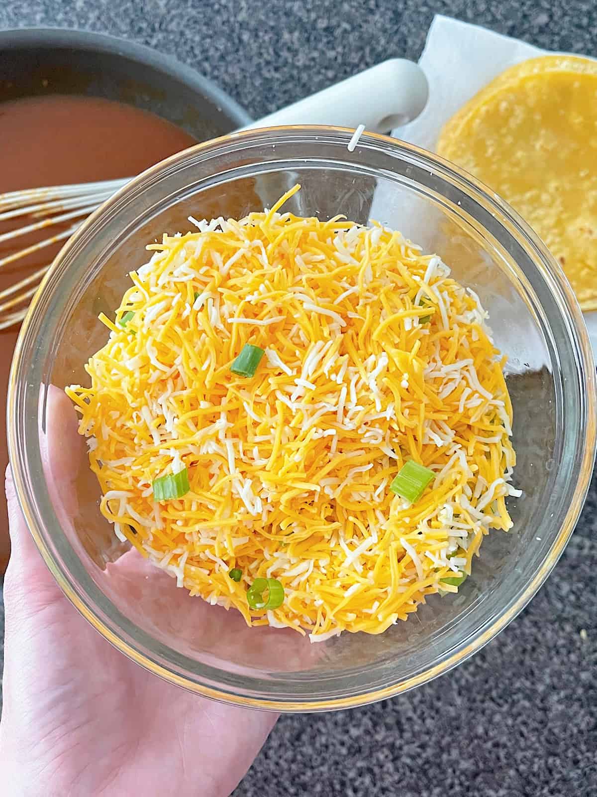 A bowl of shredded cheese and chopped green onion.