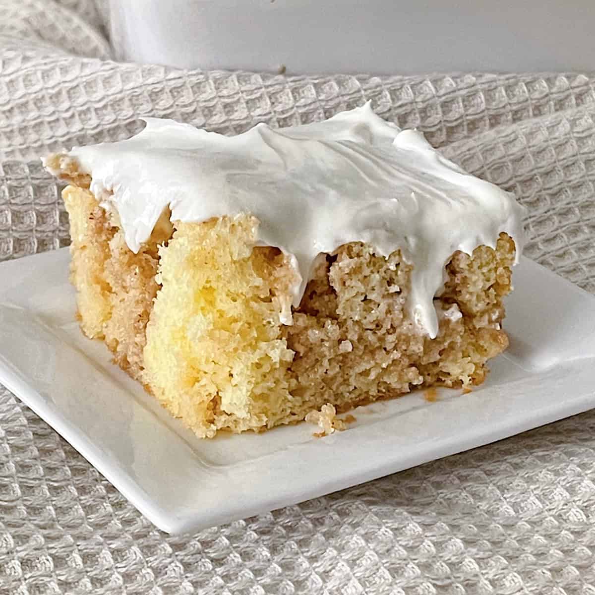 A slice of cinnamon roll poke cake with cream cheese frosting.