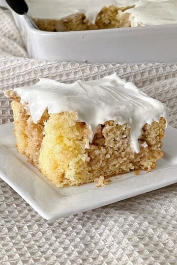 A slice of cinnamon roll poke cake with cream cheese frosting.