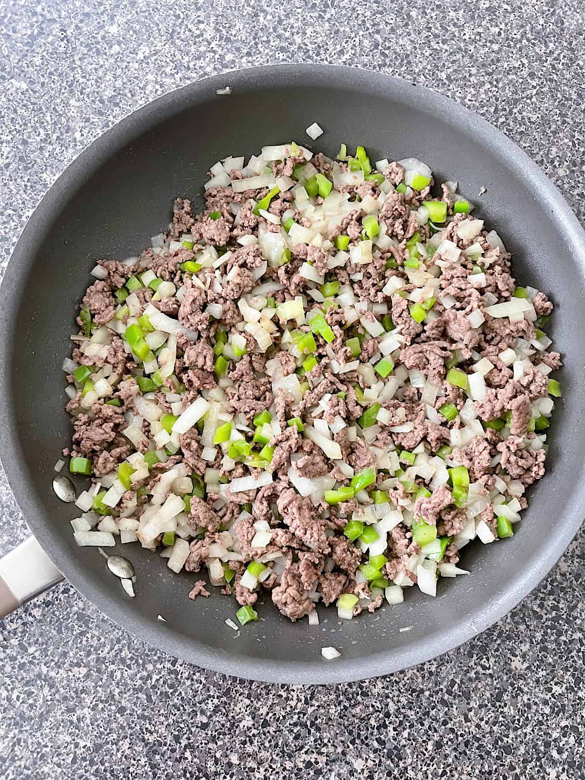 Ground Beef, diced onion, and diced green peppers in a large skillet.