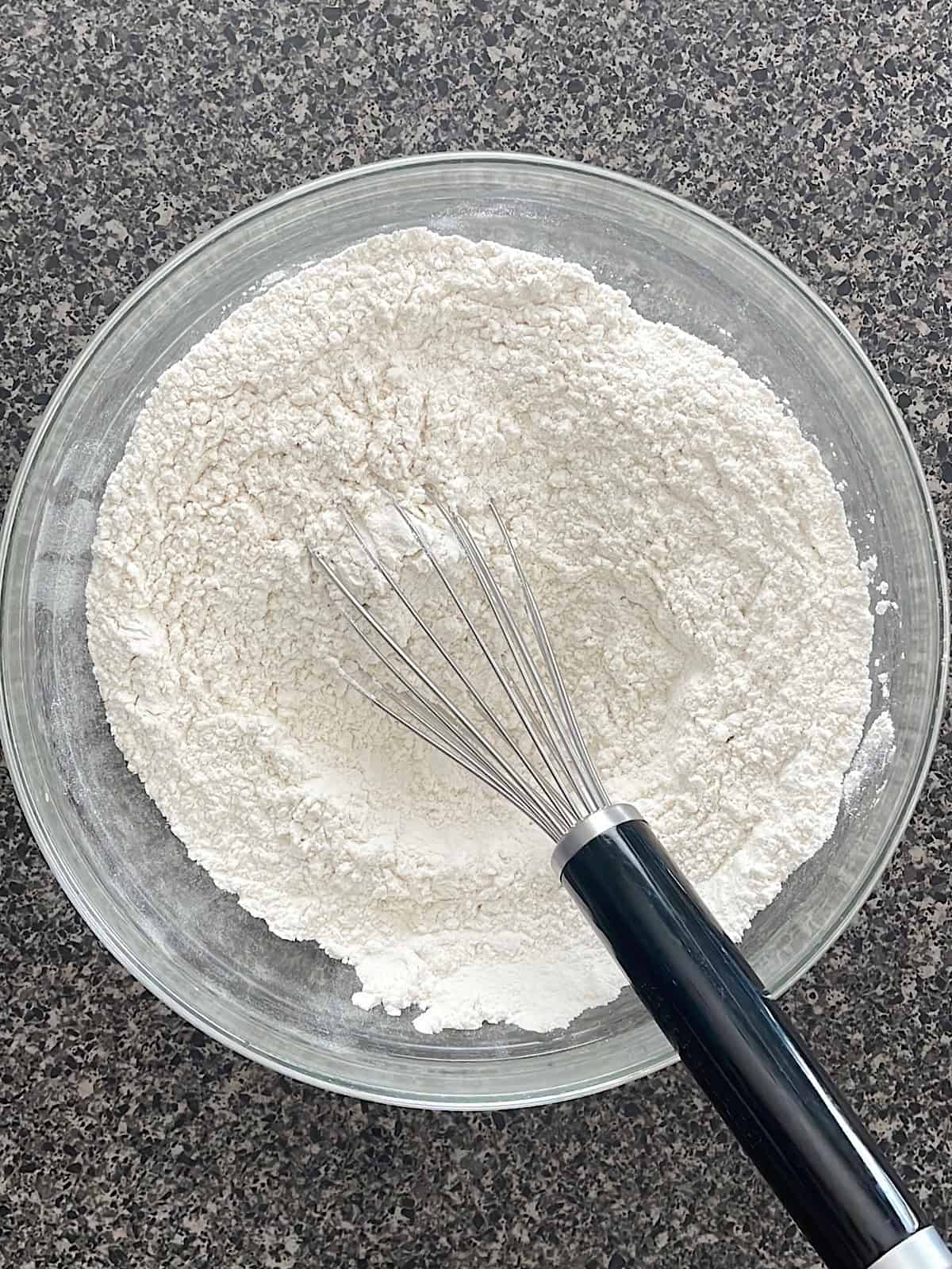Dry ingredients for cookies in a bowl with a whisk.