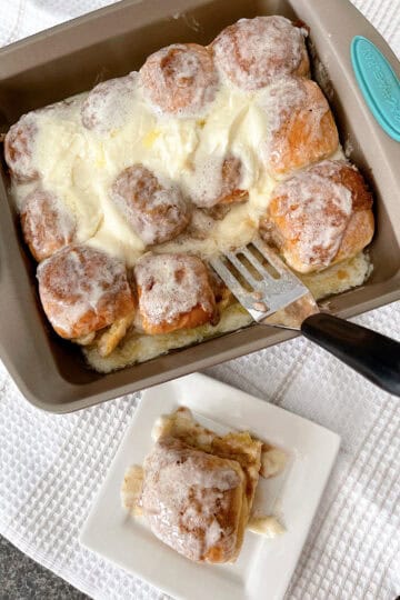Hawaiian rolls with cinnamon roll filling and icing in a baking pan.