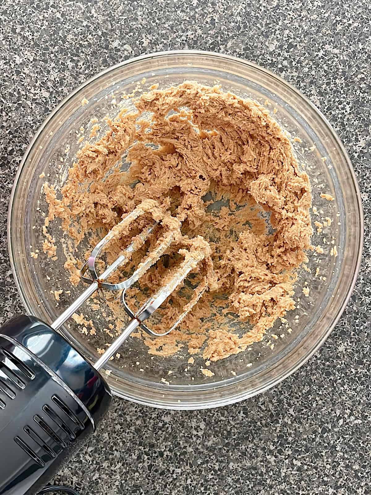 Cinnamon roll filling in a mixing bowl with an electric mixer.