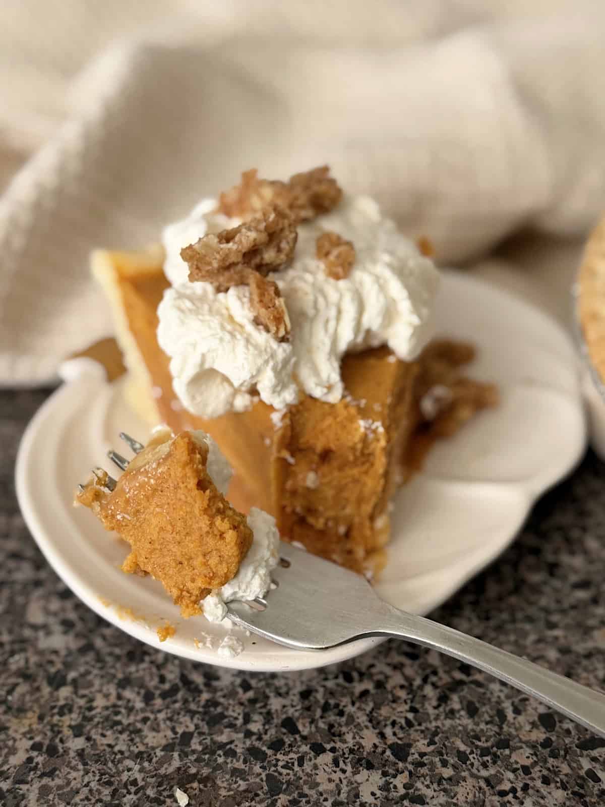 A slice of Milk Bar Pumpkin Caramel Pie topped with whipped cream and streusel.