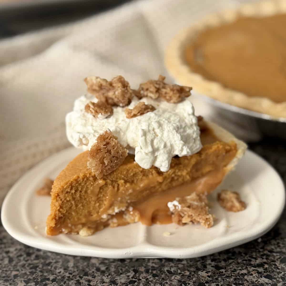 A slice of Milk Bar Pumpkin Caramel Pie topped with whipped cream and streusel.