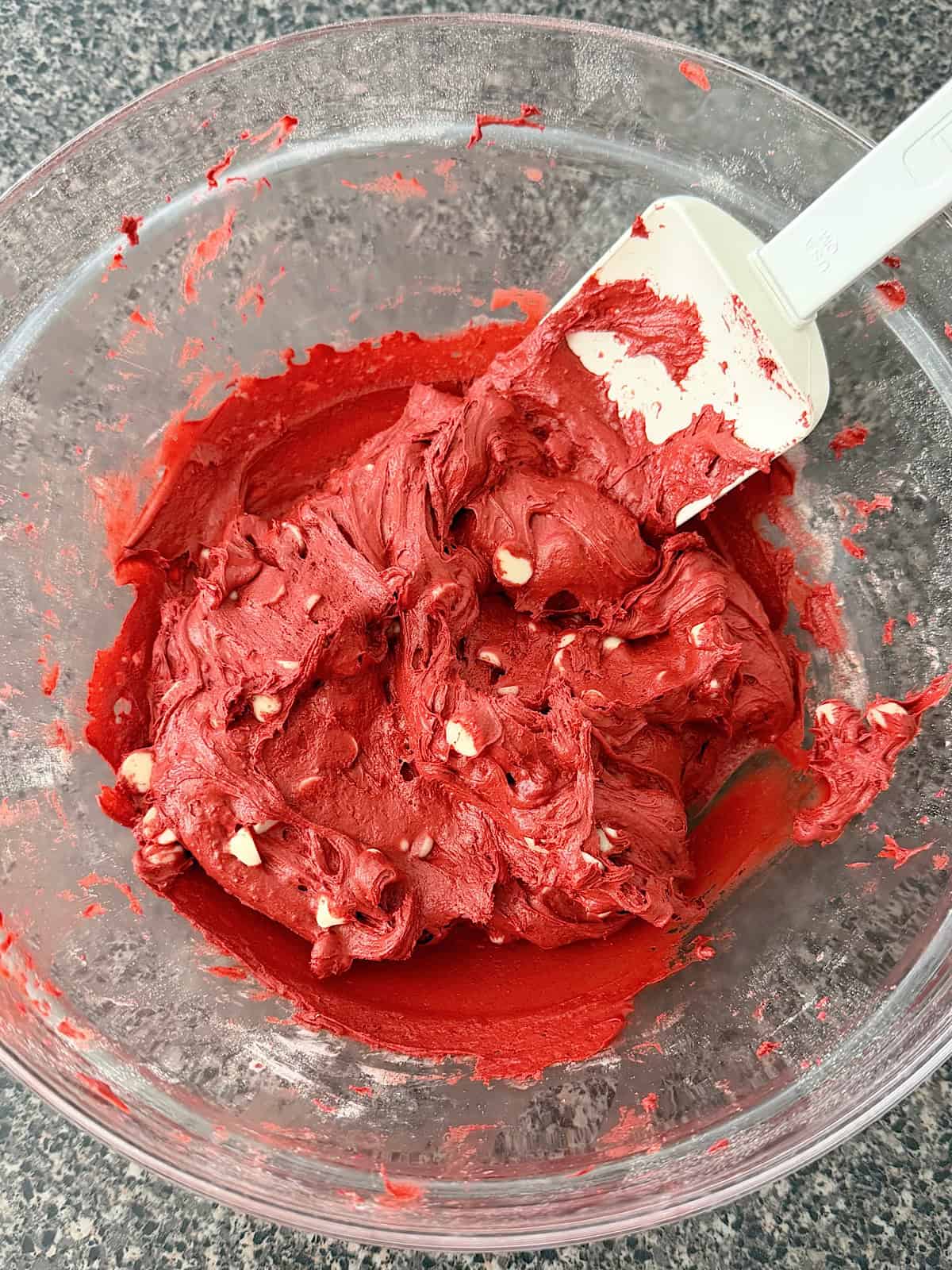 Red velvet cookie dough in a glass mixing bowl.