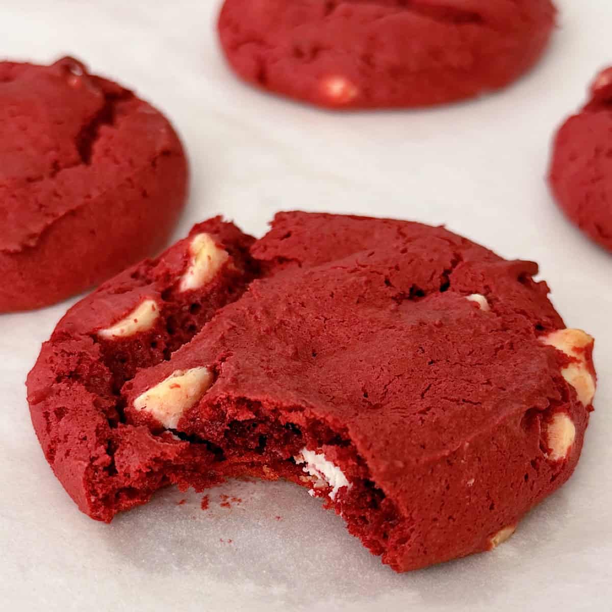 Red velvet cookies with white chocolate chips on parchment paper.