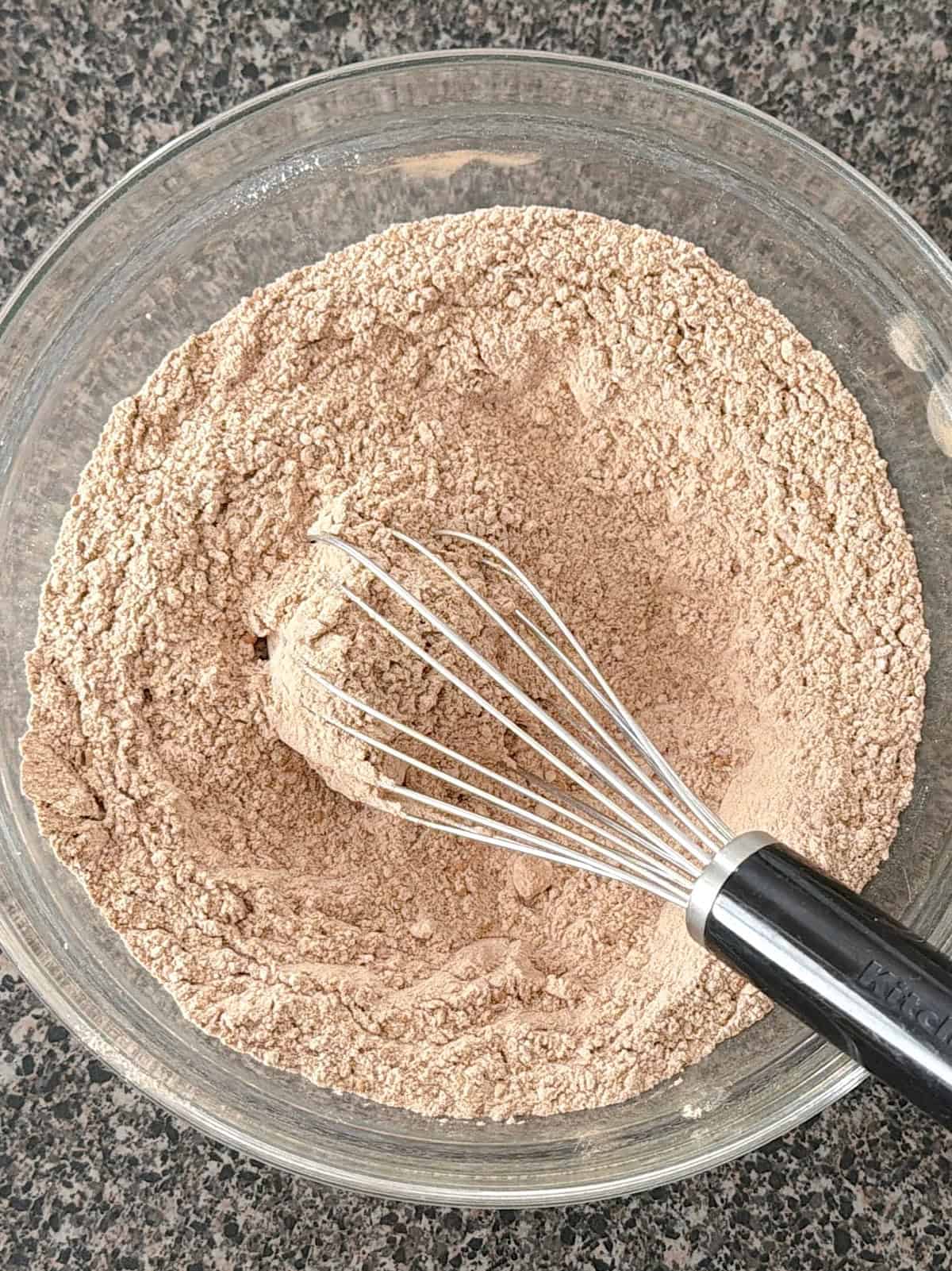 A bowl of dry ingredients with a whisk for chocolate peppermint blossoms.