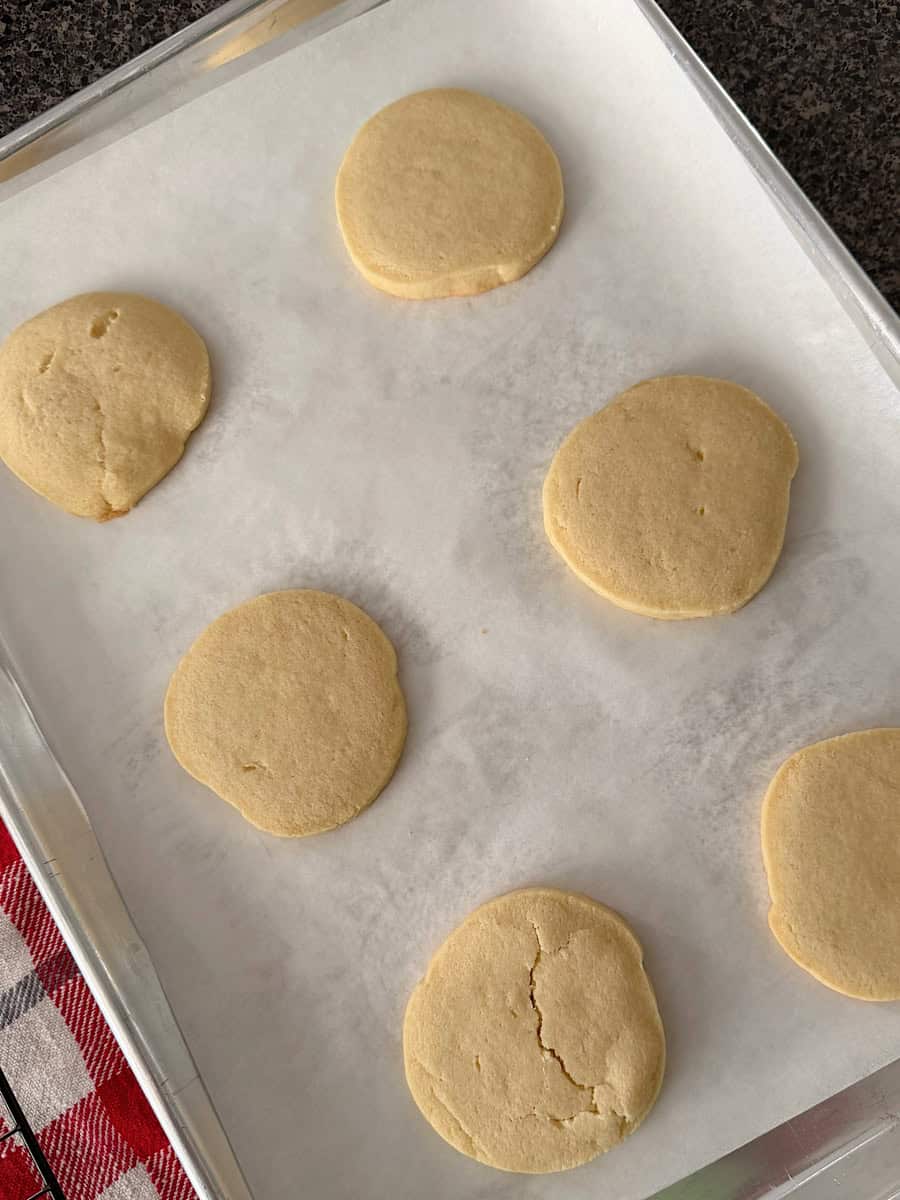 Sugar cookies on a parchment paper-lined baking sheet.