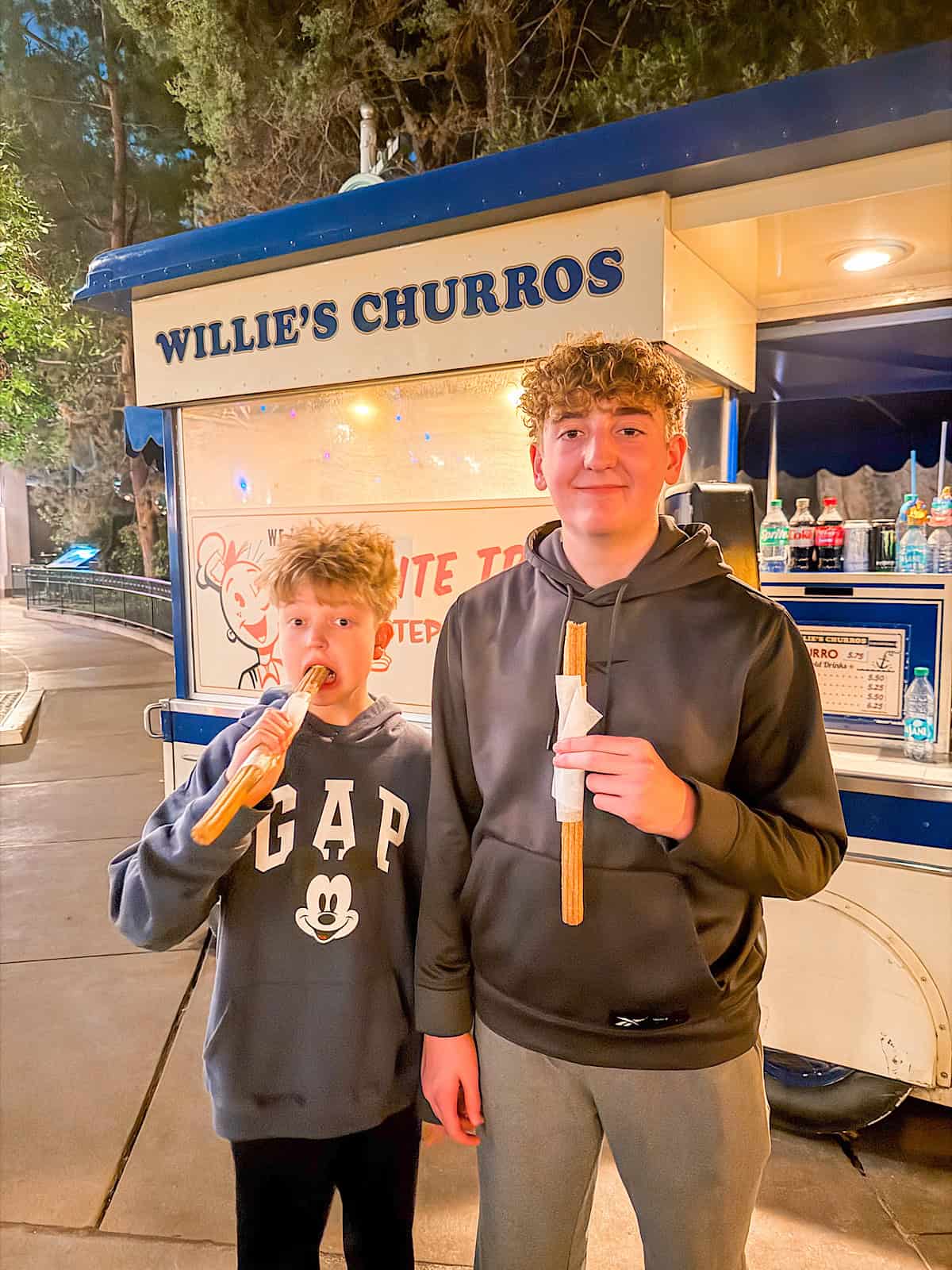 Two kids eating churros from Willie's Churro Cart at Disneyland.