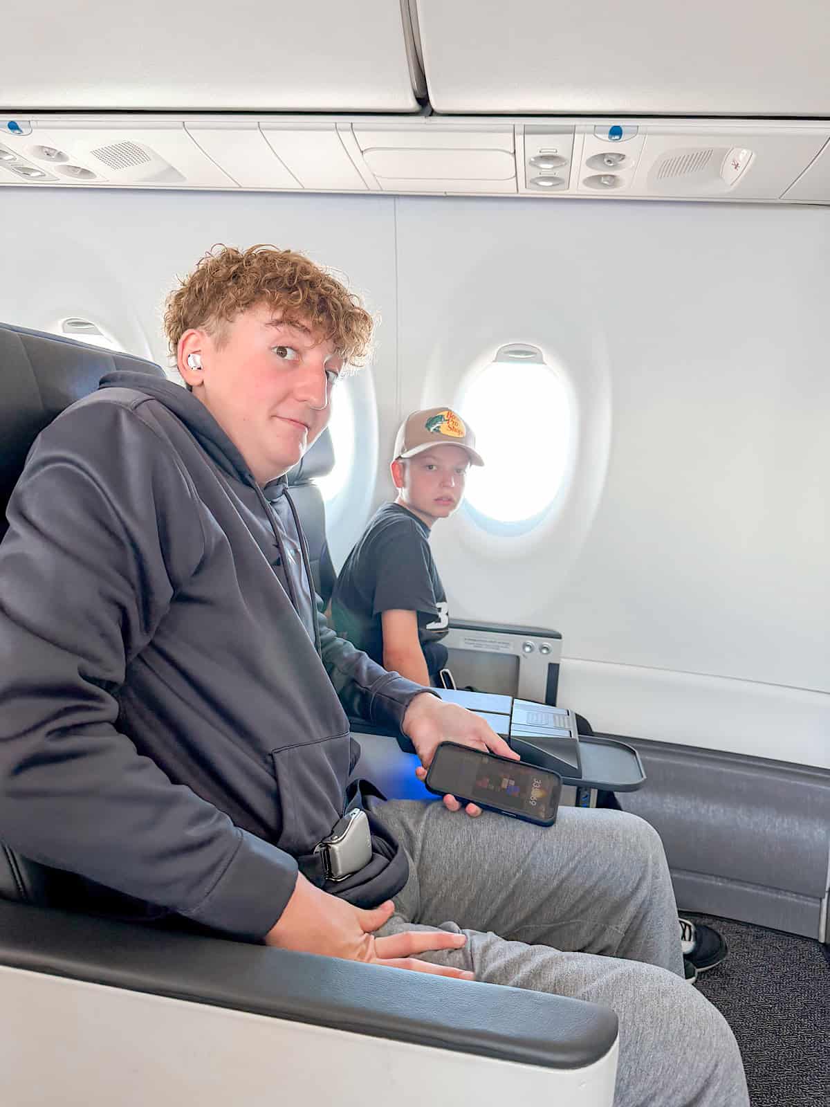 Two kids in first class seats on a Breeze Airways flight.